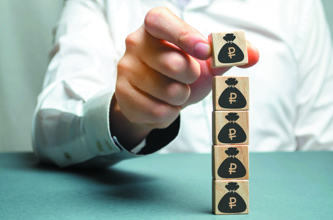 Businessman puts a block with a picture of dollars. Increased budget and profits in the team. The capital accumulation and successful business.Increase investment fund. Saving money. Economic boom