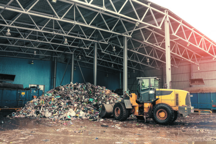 The bulldozer will clean the waste dump. Waste processing plant. Technological process. Business for sorting and processing of waste.